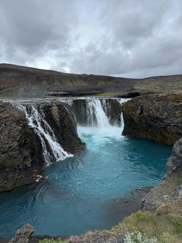 The turquoise Sigöldufoss waterfall in the Icelandic Highlands surrounded by dark volcanic rocks