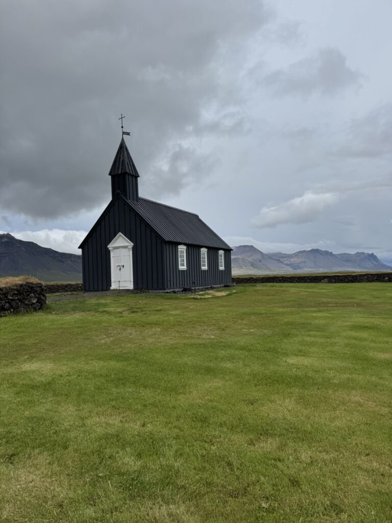 The iconic black wooden church Budakirkja surrounded by lava fields on the Snaefellsnes Peninsula