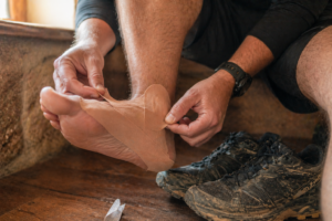 Hiker applying kinesiology tape to foot before stage on the Fishermen's Trail Portugal