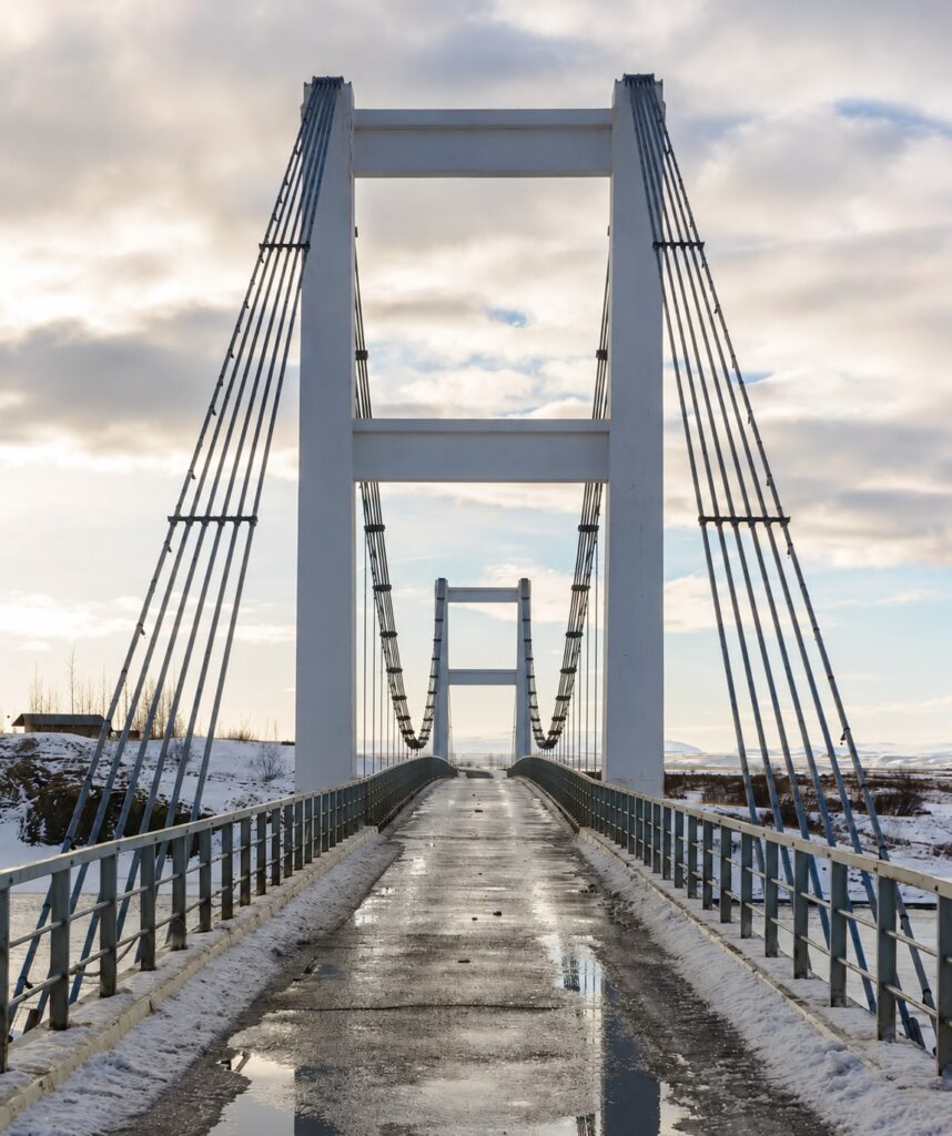 A one-lane suspension bridge in Iceland in winter, seen head-on from the approach